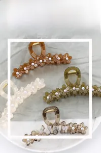 Detail showing four flower hair claws with pearls in brown, green, cream and grey colors