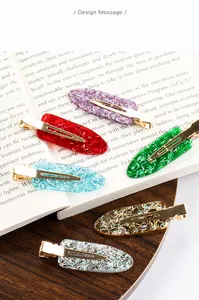 Detailansicht bunter Glitzer-Haarspangen aus Kunstharz auf einem Buch und Holztisch