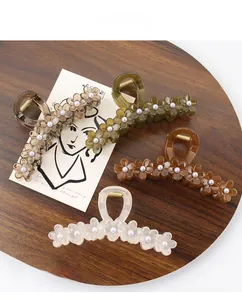 Close-up of resin flower hair claws with pearl accents on a wooden tray