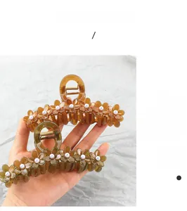 Detailed view of jelly-colored flower hair claws with pearls in amber and olive green