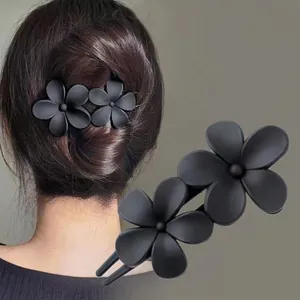 Close-up of matte black dual flower hair clip with secure double-tooth comb for hair styling