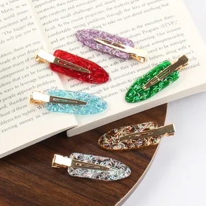 Set van zes glitter haarspelden van hars in diverse kleuren op een vintage boek