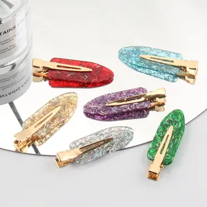 Zes glitterende acryl haarklemmen in diverse kleuren gepresenteerd op een ronde spiegel