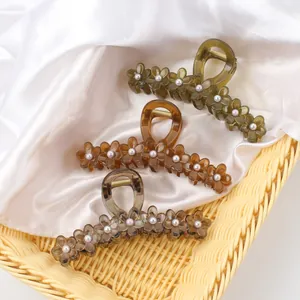 Set of three jelly-colored floral hair claws with pearls on white satin background