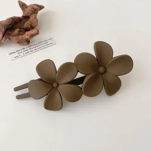Detail view of a matte dark brown double flower hair clip with a minimalist forest style