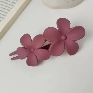 Detail of matte dark pink hair claw with dual flower design for elegant hairstyles