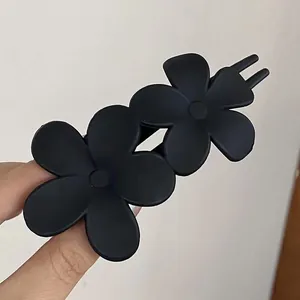 Detail view of the matte black double flower hair clip with a minimalist textured finish
