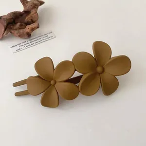 Close-up of caramel matte flower hair clip on a minimalist cream-colored background