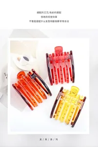 Détail de trois grandes pinces à cheveux en résine translucide rouge, ambre et jaune