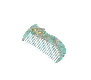 Detail of elegant acetate hair comb with golden cat face and green marble texture