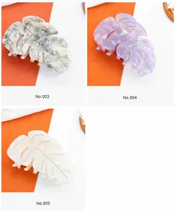 Detailed leaf-shaped acetate hair claws in marble grey, iridescent purple, and white