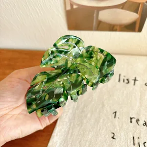 Macro detail of leaf-shaped hair claw clip with green marble acetate pattern texture