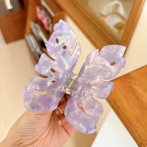Macro detail of a large iridescent purple butterfly hair claw clip with golden spring