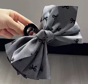 Close-up of large grey bow hair claw clip with black butterfly print for elegant styling