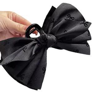 Large black bow claw clip with embroidered fabric texture for thick hair styling