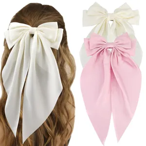 Macro detail of oversized satin bow hair clip with long streamers in beige and pink