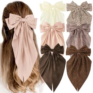 Detail of oversized satin bow hair clips in solid colors and leopard prints set