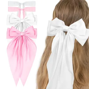 Detail showing oversized satin bow hair clip in white and pink on long wavy hair