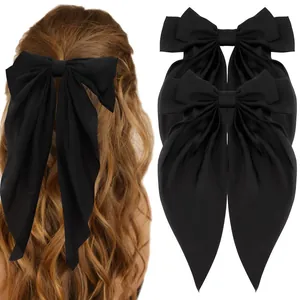 Detail of oversized black satin bow hair clips with long ribbons on female model back