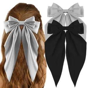 Detailed view of oversized satin bow hair clips in silver grey and classic black
