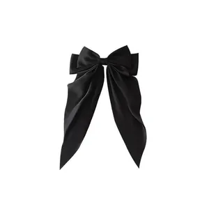 Elegant oversized black satin bow hair clip with long ribbons on white background