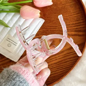 Détail de la pince à cheveux rose et transparente avec mécanisme à ressort doré