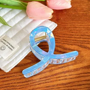 Détail d'une pince à cheveux bleue irisée avec ressort doré sur table en bois