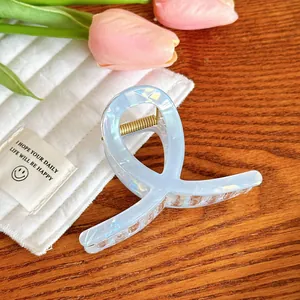 Détail d'une pince à cheveux bleu clair en acétate avec design croisé sur fond esthétique