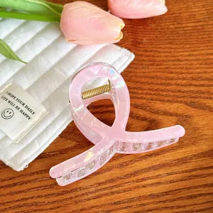 Détail de la pince à cheveux rose nacré avec design croisé sur table en bois