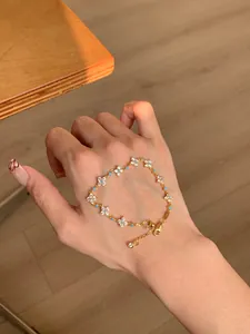 Detailed view of an 18k gold plated flower bracelet with cubic zirconia on a hand