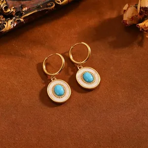 Detailopname van vintage gouden oorringen met turquoise stenen en wit inlegwerk