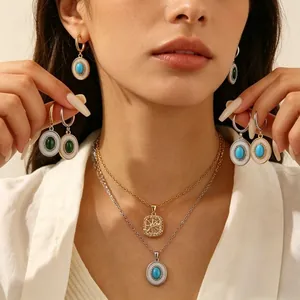 Detailweergave van turquoise en smaragdgroene ovale oorbellen met kristallen accenten
