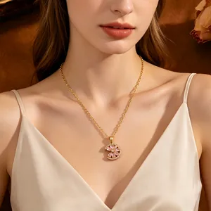Elegante gouden ketting met roze kristallen bloem en halve maan hanger gedragen door model