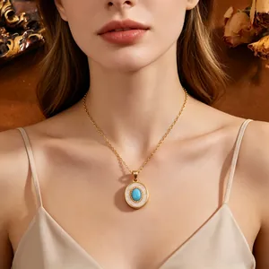 Detailweergave van een gouden halsketting met ovale hanger van turkoois en parelmoer.
