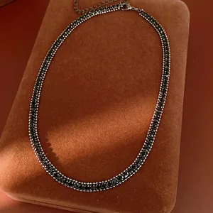 Nahaufnahme einer eleganten schwarzen Strass-Halskette auf einem braunen Schmuckpad.