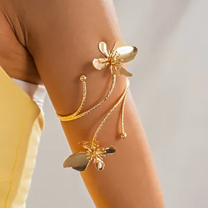 Detail van een gouden metalen bloemarmband elegant om de bovenarm van een model gewikkeld