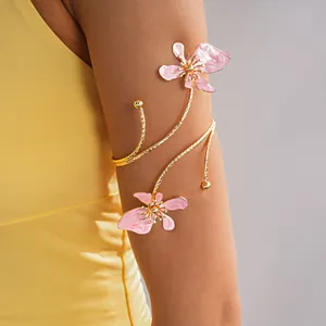 Detail van een elegante goudkleurige bovenarmband met roze geëmailleerde bloemen.