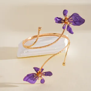 Gedetailleerd overzicht van gouden spiraalarmband met paarse geëmailleerde bloemen