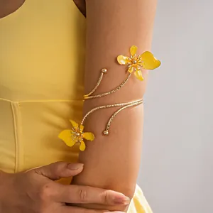 Detail van een elegante gouden metalen armring met levendige gele geëmailleerde bloemen.