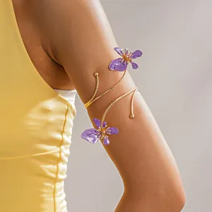 Detailopname van een gouden bovenarmband met elegante paarse bloemen van emaille