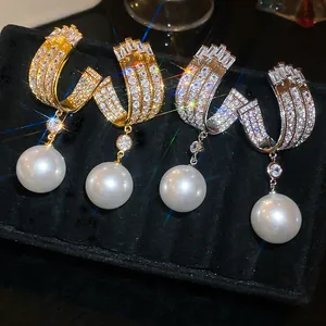 Dettaglio di orecchini geometrici di lusso in oro e argento con zirconi e perle