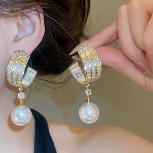 Dettaglio degli orecchini a cerchio in zircone di lusso con perla bianca pendente