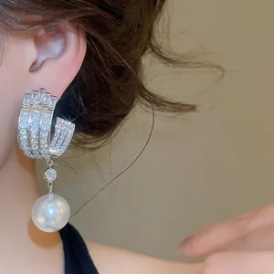 Primo piano di un orecchino di lusso francese con zirconi e una perla pendente
