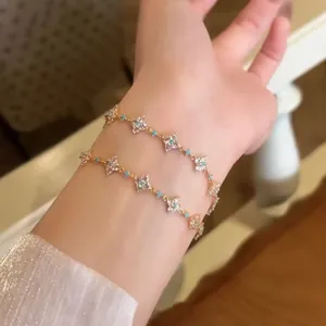 Elegant close-up view of two 18k gold-plated zircon clover bracelets worn on a wrist.
