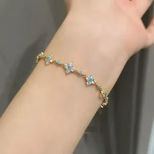 Close-up of elegant 18k gold plated clover bracelet with zircon and turquoise stones.