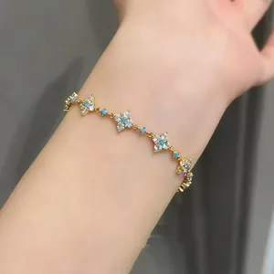 Close-up of gold-plated clover bracelet with turquoise and sparkling zircon accents