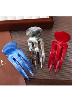 Détails de pinces à cheveux marbrées en bleu, beige et rouge sur plateau bois