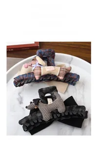Detail of plaid fabric hair claws featuring plush dog charms and handmade labels