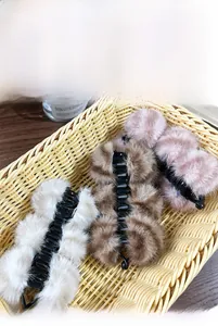Détail de pinces à cheveux banane en peluche beige, marron et rose pour coiffure d'hiver douce