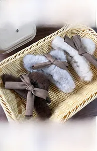 Detail view of plush bow claw clips in dark brown, grey blue, and beige colors